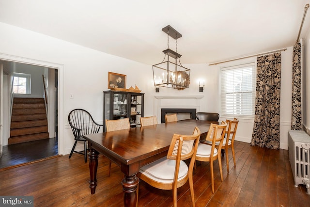 dining area with radiator, an inviting chandelier, and dark hardwood / wood-style floors