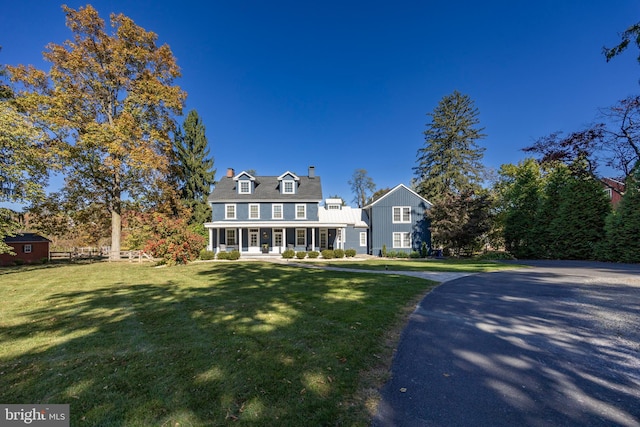 new england style home with a porch and a front lawn