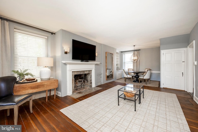 living room featuring an inviting chandelier, dark hardwood / wood-style floors, and a tiled fireplace