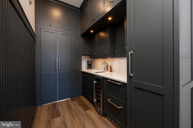 bar featuring wine cooler, sink, light hardwood / wood-style floors, and tasteful backsplash