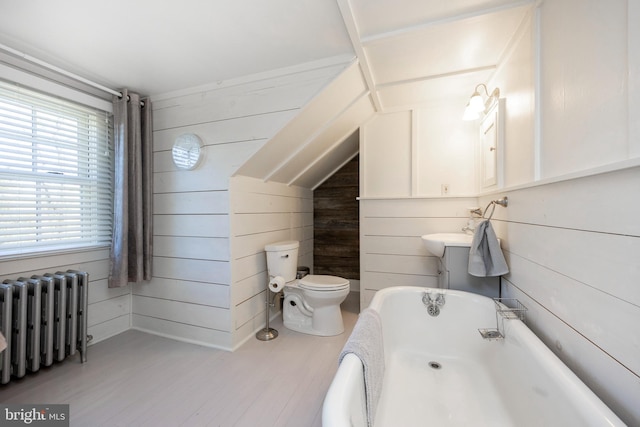 bathroom with a bath, hardwood / wood-style floors, radiator, toilet, and wooden walls