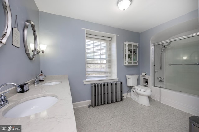 full bathroom featuring toilet, radiator heating unit, bath / shower combo with glass door, and vanity