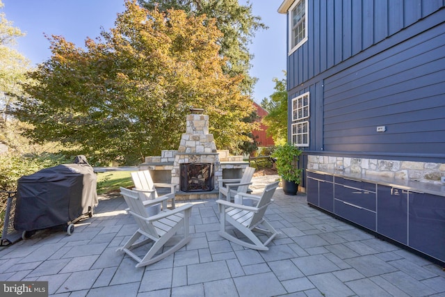 view of patio with grilling area and an outdoor stone fireplace