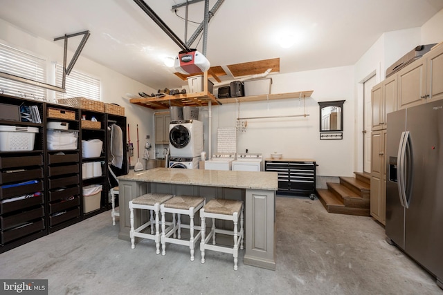 interior space featuring a garage door opener, stainless steel fridge, and stacked washer and dryer