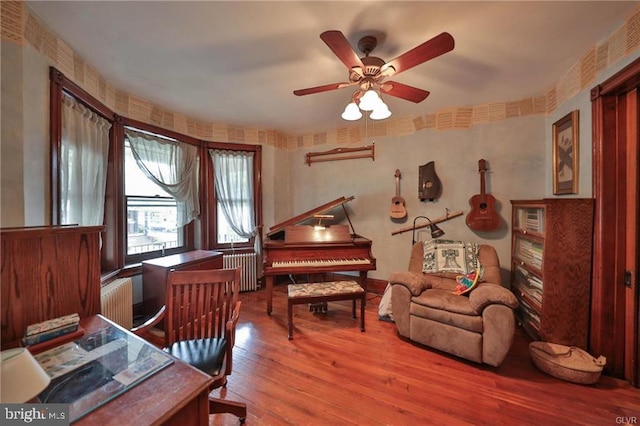 office area featuring hardwood / wood-style floors, radiator heating unit, and ceiling fan