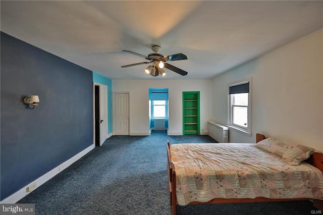 unfurnished bedroom with dark carpet, multiple windows, radiator heating unit, and ceiling fan