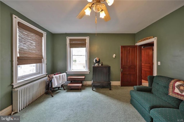 living area with ceiling fan, radiator heating unit, plenty of natural light, and carpet floors