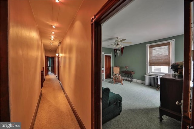 hallway with light colored carpet and radiator