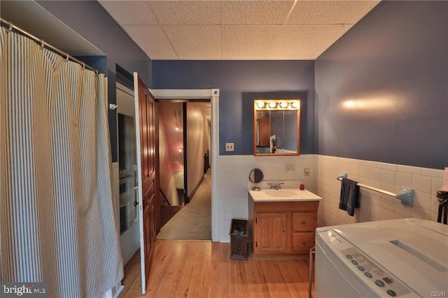 bathroom with vanity, tile walls, wood-type flooring, and washer / dryer