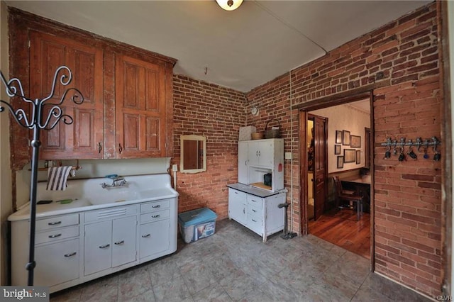 kitchen featuring white cabinetry and brick wall