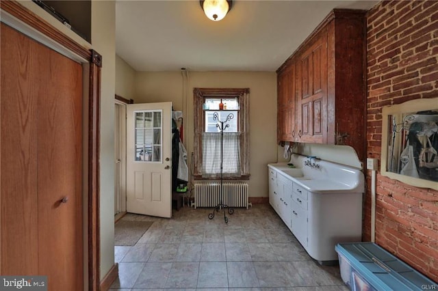 washroom featuring brick wall and radiator