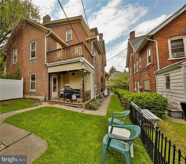 back of property with a patio, a yard, and a balcony