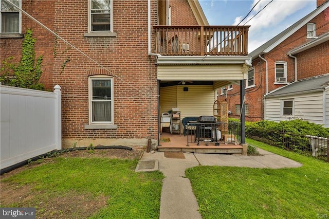 rear view of property featuring a balcony, a patio area, and a lawn