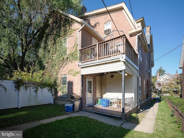 back of property featuring a balcony and a lawn