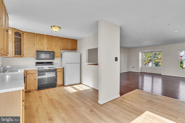 kitchen with light hardwood / wood-style floors, range with gas stovetop, white fridge, and sink