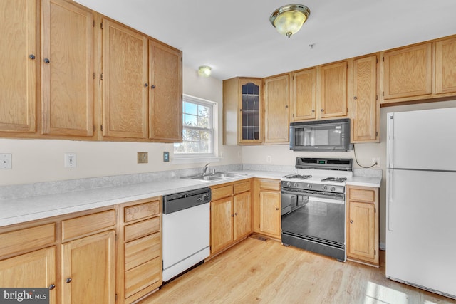 kitchen with sink, black appliances, light brown cabinets, and light hardwood / wood-style floors