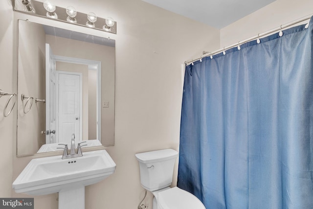 bathroom featuring toilet, sink, and curtained shower