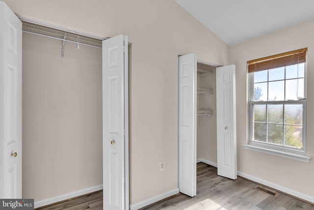 unfurnished bedroom featuring a closet, light hardwood / wood-style floors, and lofted ceiling