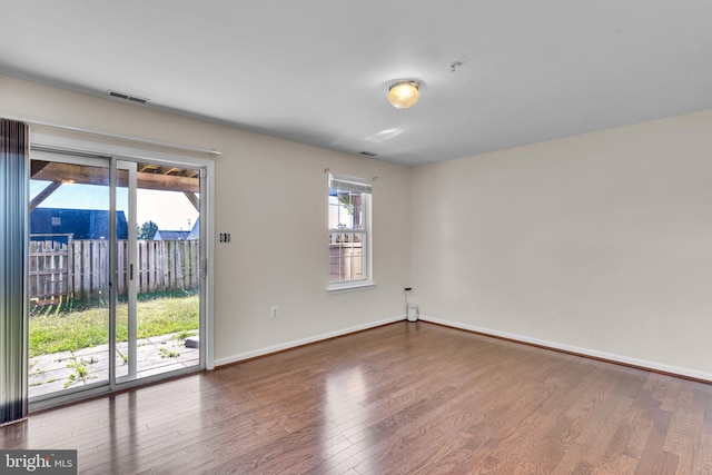 empty room with hardwood / wood-style floors and a healthy amount of sunlight