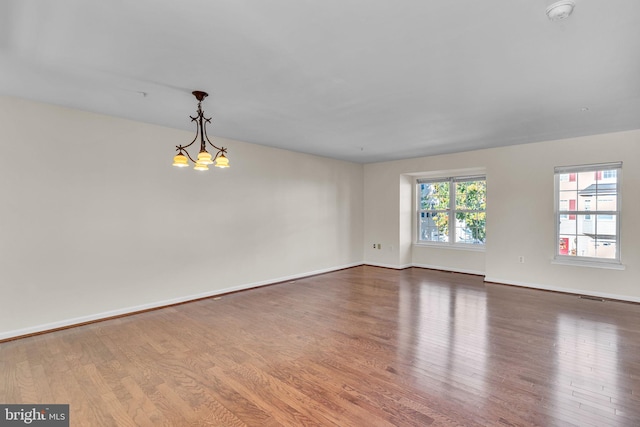 unfurnished room with hardwood / wood-style floors and a chandelier