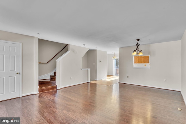 unfurnished living room featuring a chandelier and wood-type flooring