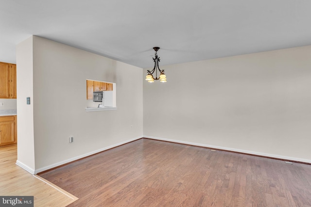 unfurnished room with a chandelier and light hardwood / wood-style floors