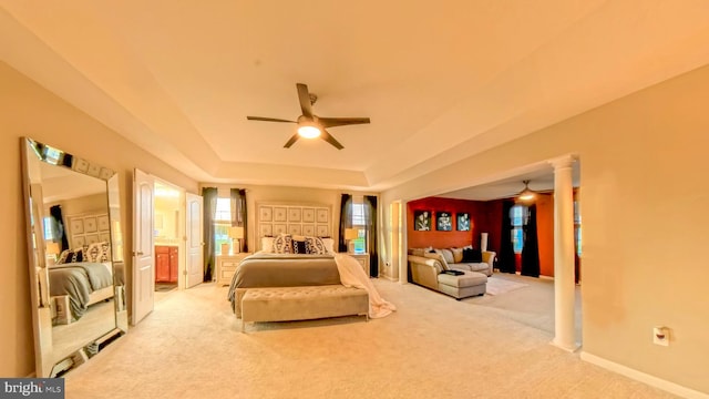 carpeted bedroom featuring ceiling fan, a tray ceiling, and decorative columns