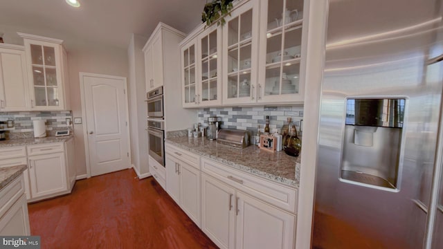 kitchen featuring white cabinets, backsplash, dark hardwood / wood-style flooring, stainless steel appliances, and light stone counters