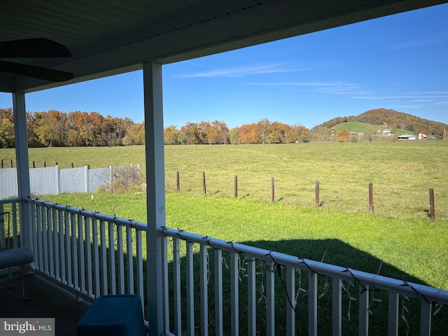 view of yard with a rural view, a wooden deck, and ceiling fan