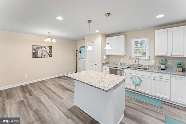 kitchen featuring a center island, sink, decorative light fixtures, and white cabinets