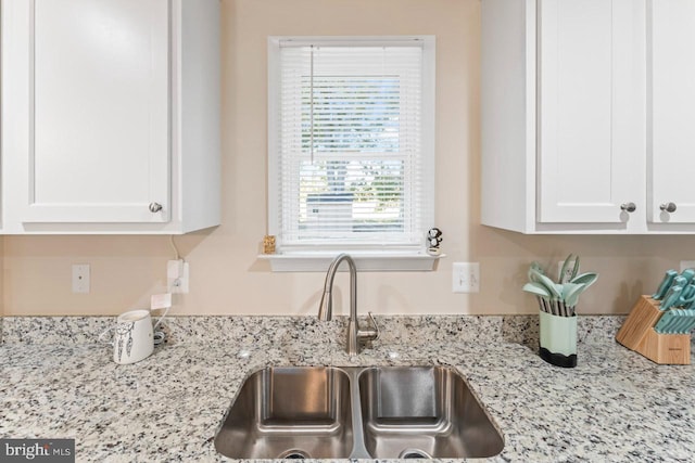 details with light stone counters, sink, and white cabinets