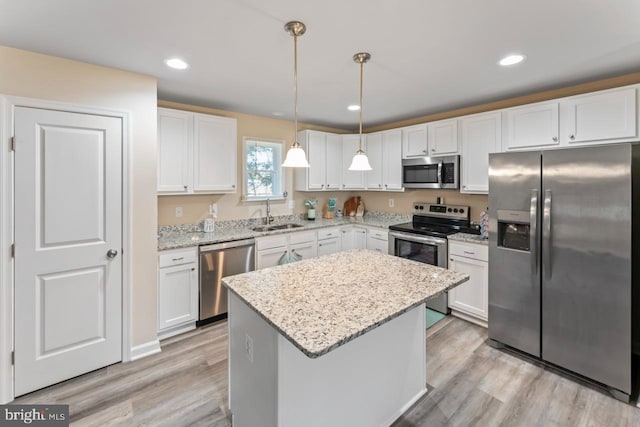 kitchen featuring appliances with stainless steel finishes, white cabinetry, a center island, and pendant lighting