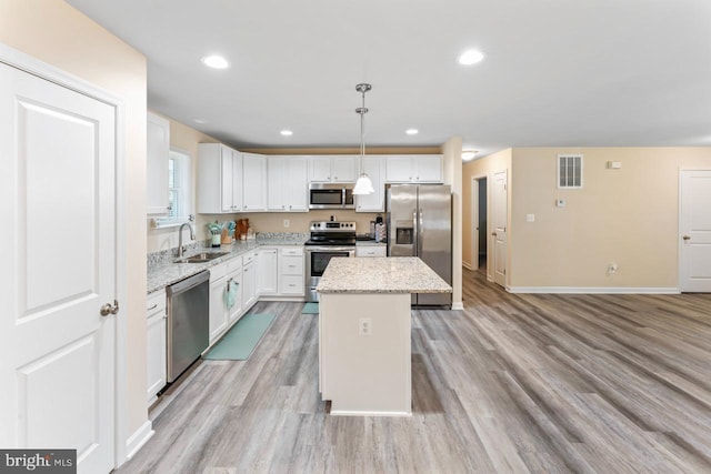 kitchen with sink, a center island, pendant lighting, white cabinetry, and appliances with stainless steel finishes