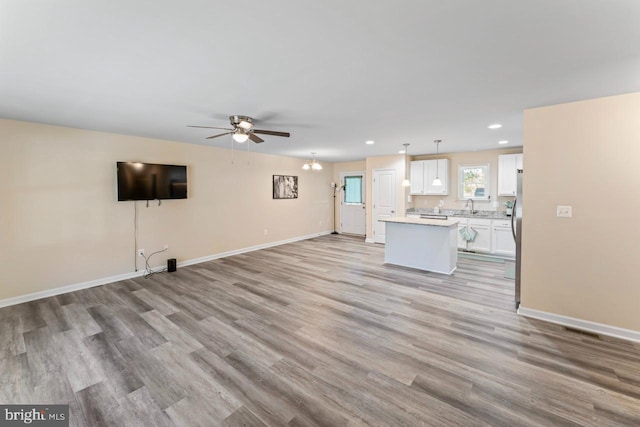 unfurnished living room featuring sink, light hardwood / wood-style floors, and ceiling fan