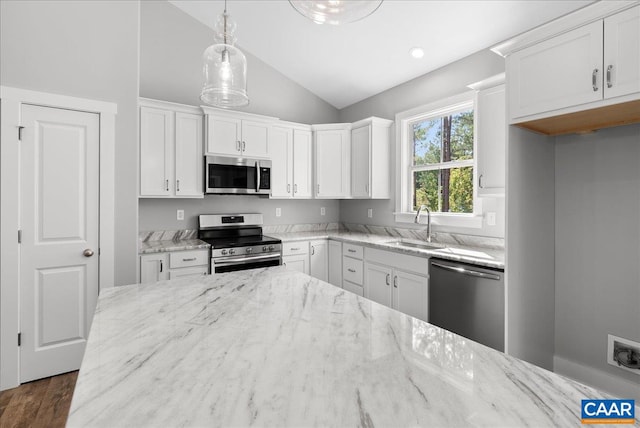 kitchen featuring lofted ceiling, appliances with stainless steel finishes, decorative light fixtures, and white cabinetry