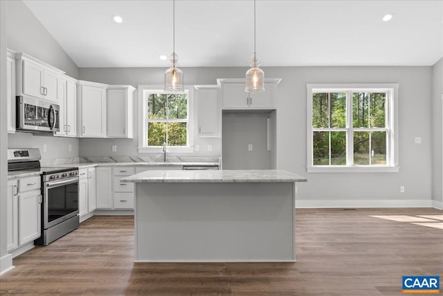 kitchen with stainless steel appliances, a center island, plenty of natural light, and white cabinets