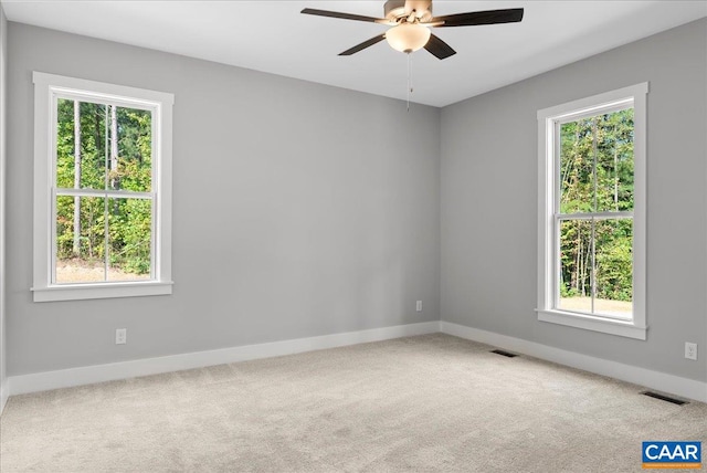 carpeted spare room featuring ceiling fan and a wealth of natural light