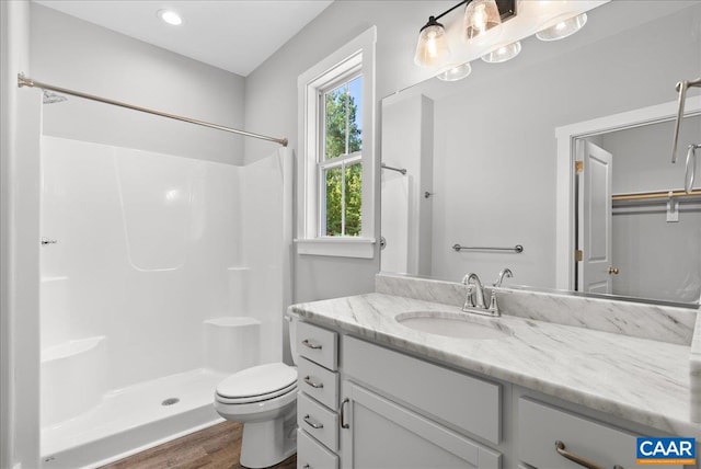 bathroom with toilet, hardwood / wood-style flooring, vanity, and a shower