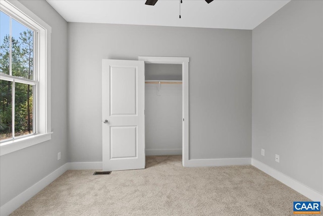 unfurnished bedroom with a closet, ceiling fan, and light carpet