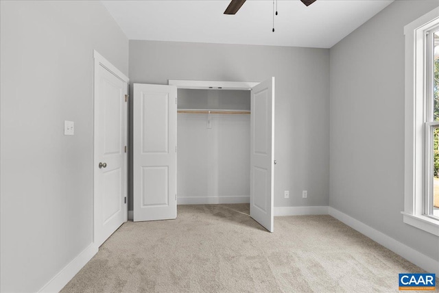 unfurnished bedroom featuring a closet, ceiling fan, multiple windows, and light colored carpet