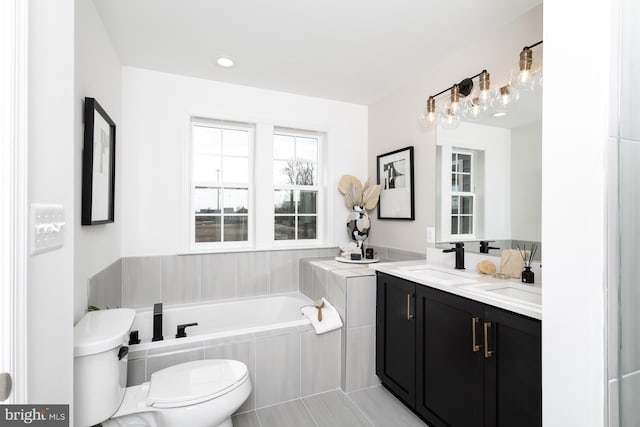 bathroom featuring toilet, a relaxing tiled tub, vanity, and tile patterned floors