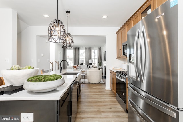 kitchen with light wood-type flooring, sink, pendant lighting, a notable chandelier, and stainless steel appliances