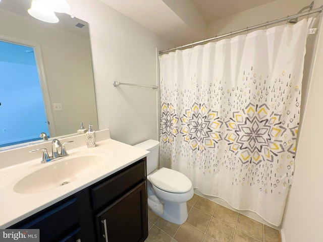 bathroom featuring a healthy amount of sunlight, toilet, tile patterned floors, walk in shower, and vanity