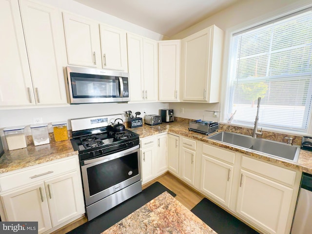 kitchen with sink, white cabinets, stainless steel appliances, and light wood-type flooring