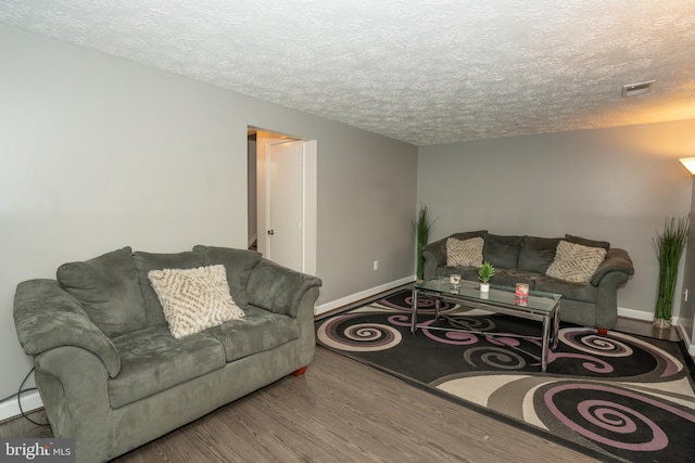 living room featuring hardwood / wood-style floors, a textured ceiling, and a baseboard heating unit