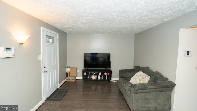 living room with a textured ceiling and dark hardwood / wood-style floors