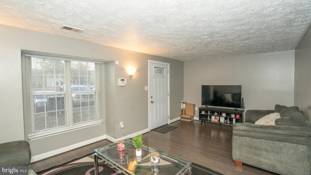 living room with dark wood-type flooring and a textured ceiling