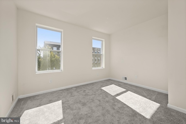 empty room featuring visible vents, baseboards, and carpet floors