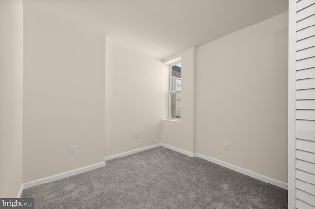 spare room featuring dark colored carpet