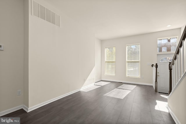 foyer entrance featuring dark wood finished floors, visible vents, a wealth of natural light, and baseboards